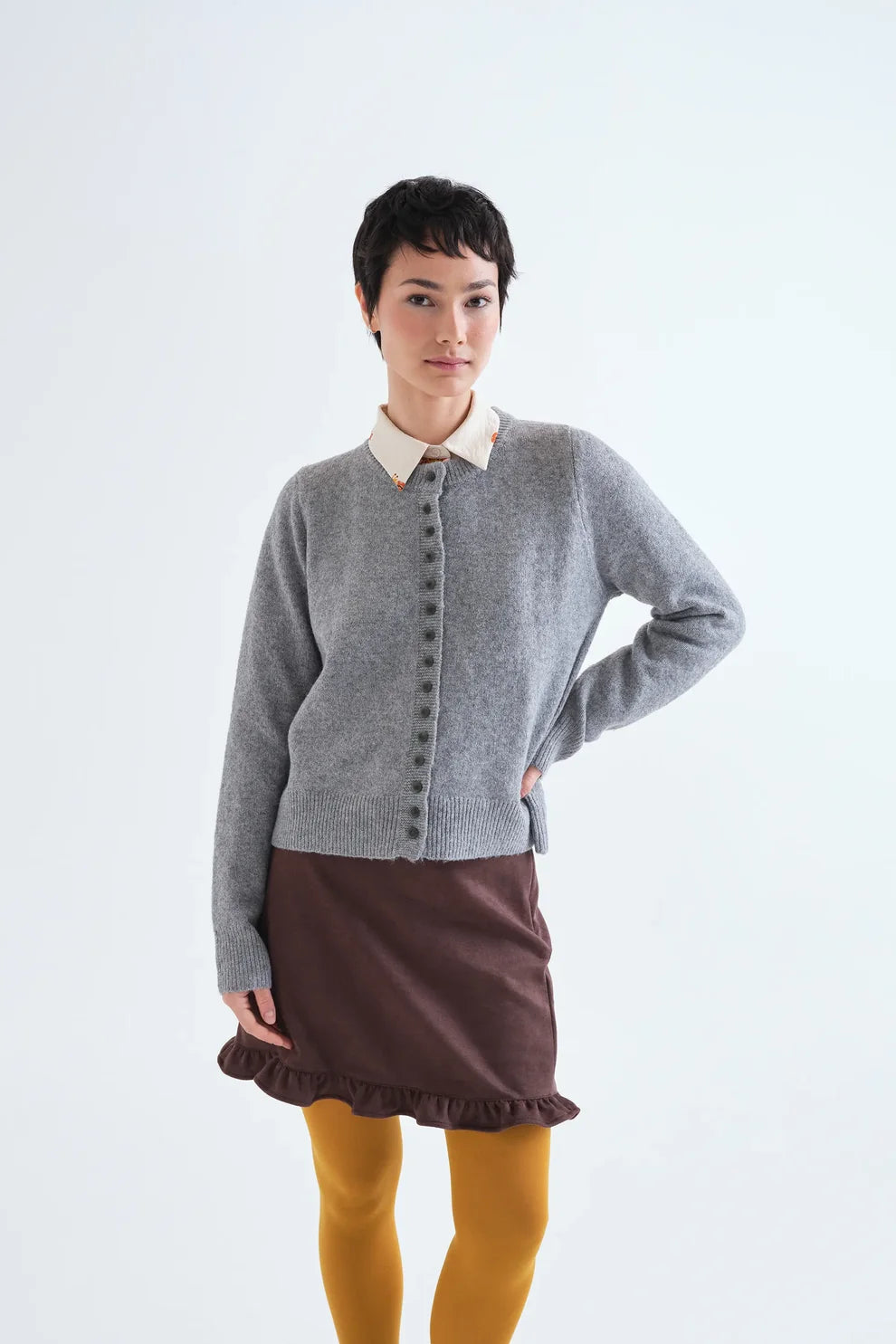 Grey knit button-front cardigan with ribbed trim layered over cream collared shirt