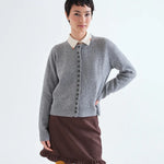 Grey knit button-front cardigan with ribbed trim layered over cream collared shirt