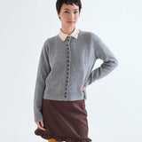 Grey knit button-front cardigan with ribbed trim layered over cream collared shirt