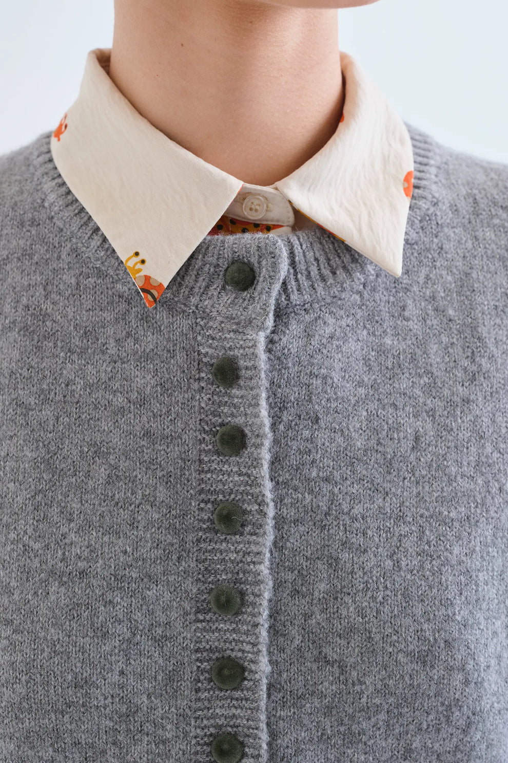 Fantastica grey knit cardigan with green buttons, layered over a floral collared shirt