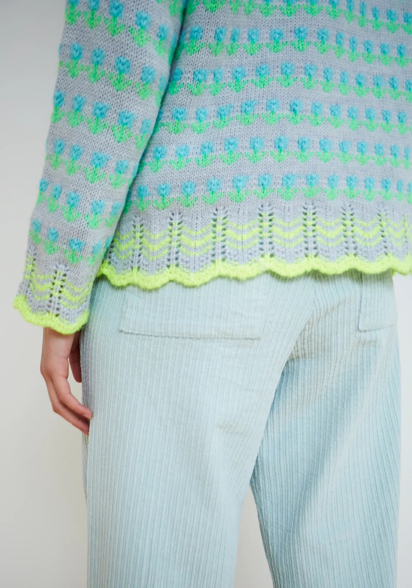 Sky blue fair isle knit sweater with neon green and turquoise pattern, scalloped hem