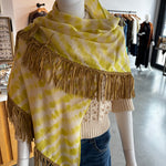Yellow tie-dye pashmina wrap scarf with tan leather fringe trim on mannequin
