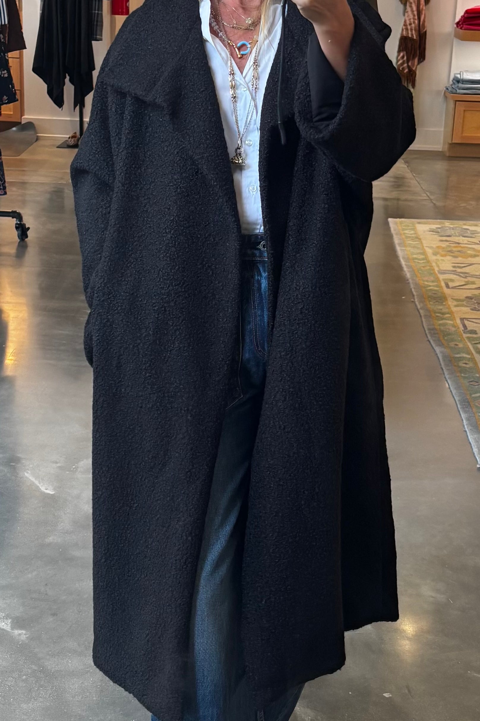 Black boucle longline overcoat worn open over white shirt and jeans