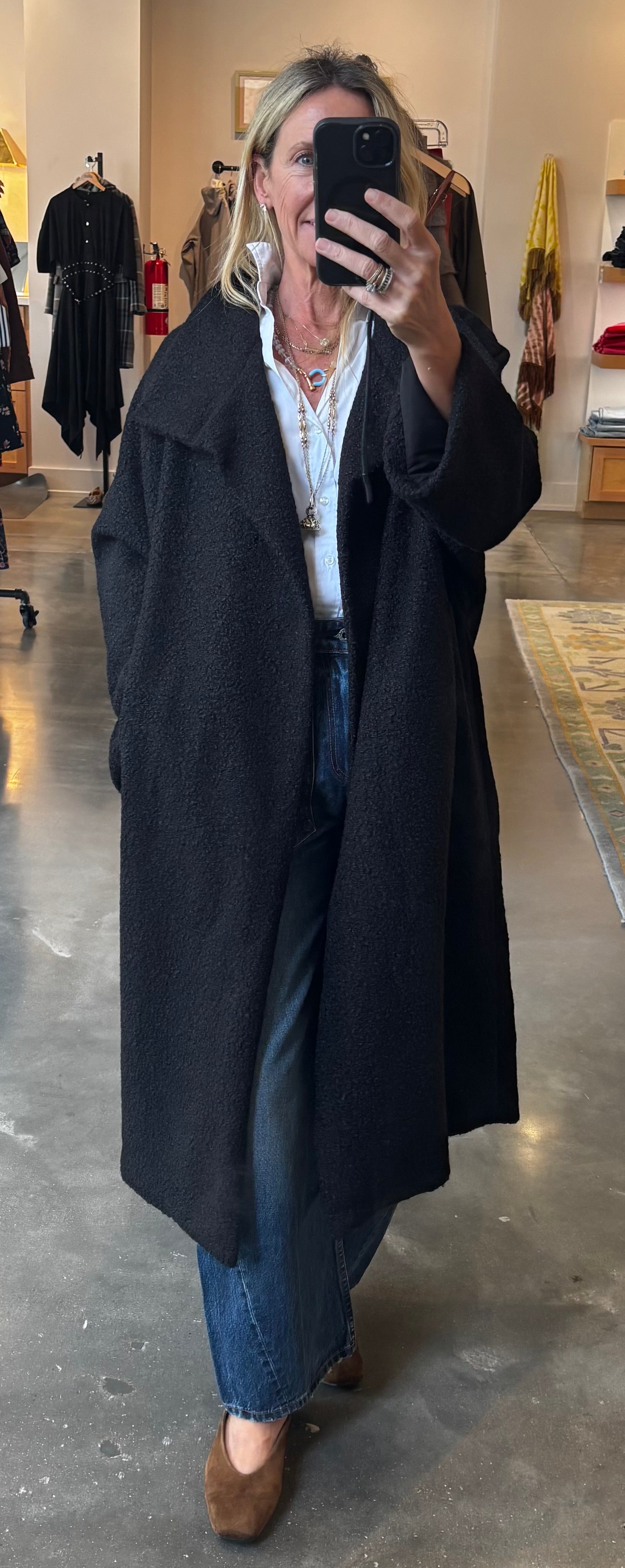 Black boucle longline overcoat worn open over white shirt and jeans