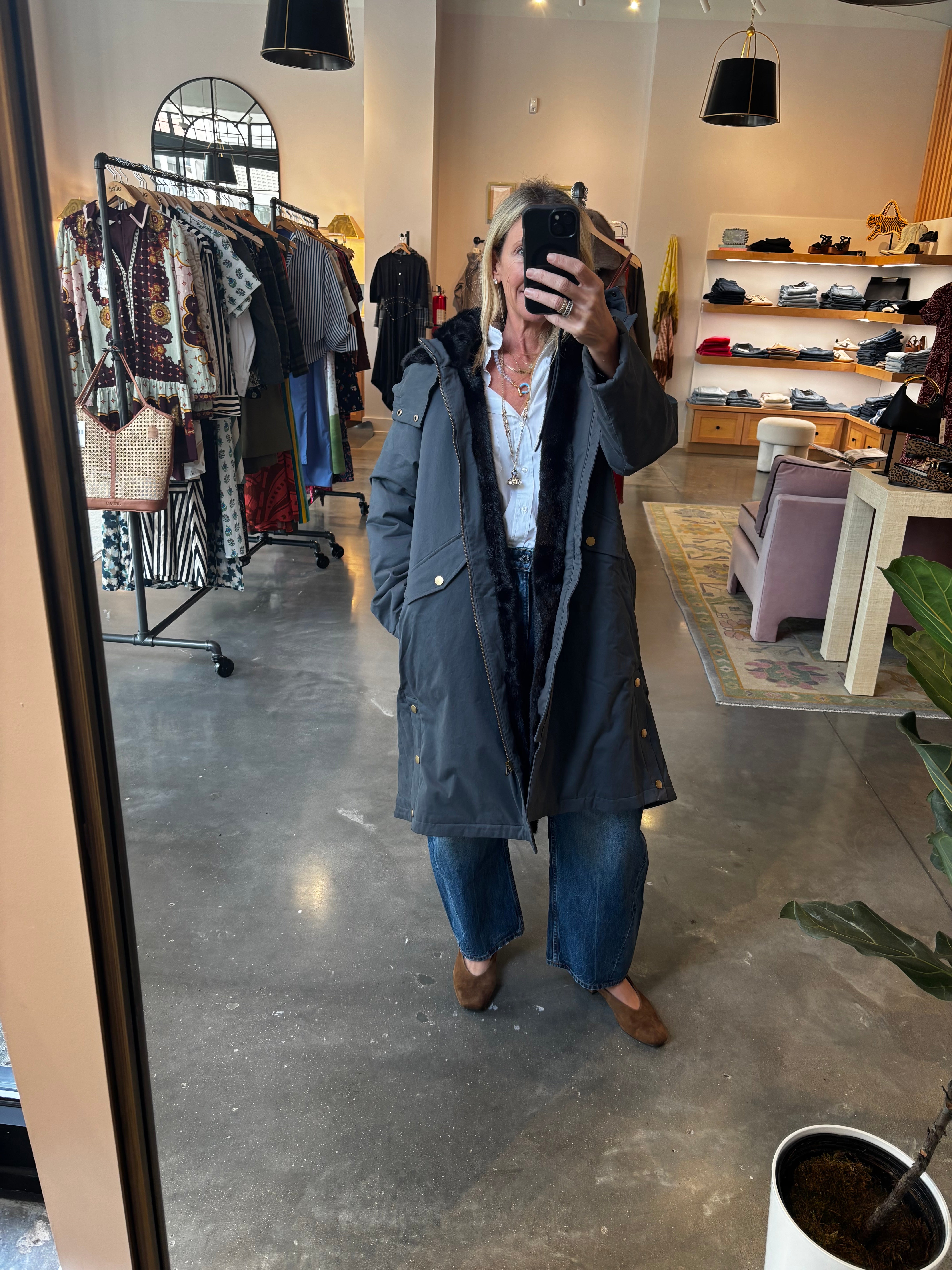Gray long reversible parka coat with faux fur lining, worn open over jeans