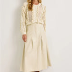 Cream vegan leather midi skirt with box pleats and fixed waistband, styled with ivory knit sweater