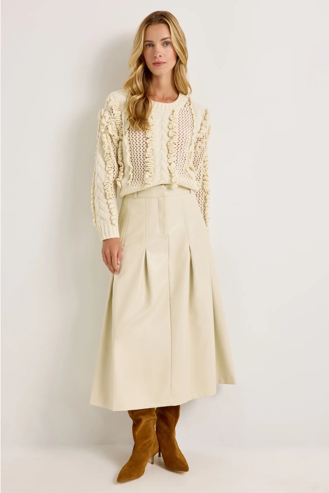 Cream vegan leather midi skirt with box pleats and fixed waistband, styled with ivory knit sweater