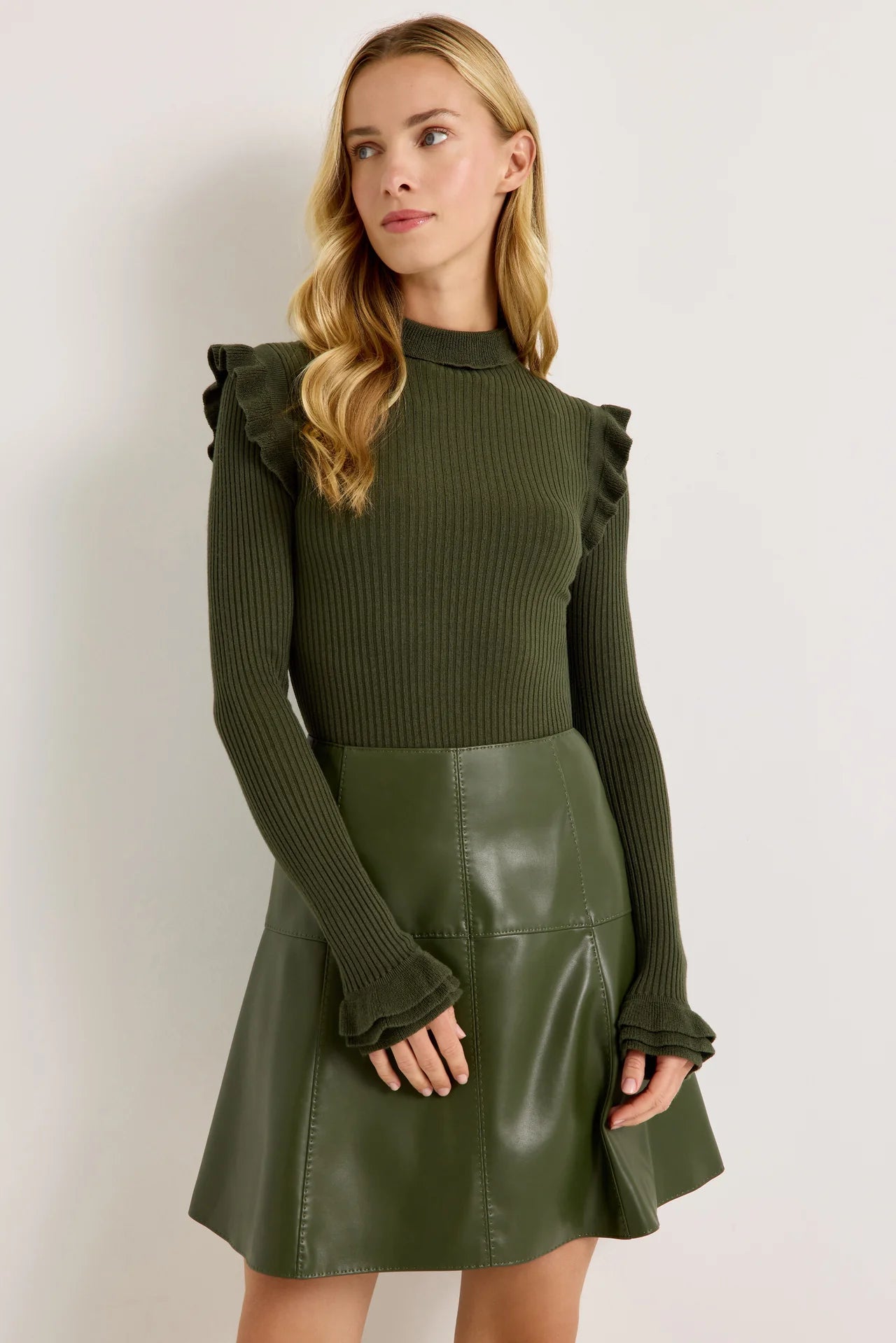 Dark green ribbed turtleneck sweater with ruffle shoulders and flared cuffs