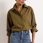 Cropped olive green cotton shirt with collar and hidden button placket paired with blue jeans