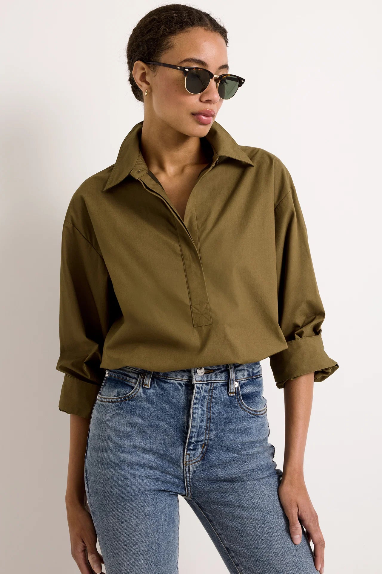 Cropped olive green cotton shirt with collar and hidden button placket paired with blue jeans