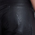 Close-up back pocket detail of black vegan leather barrel pants