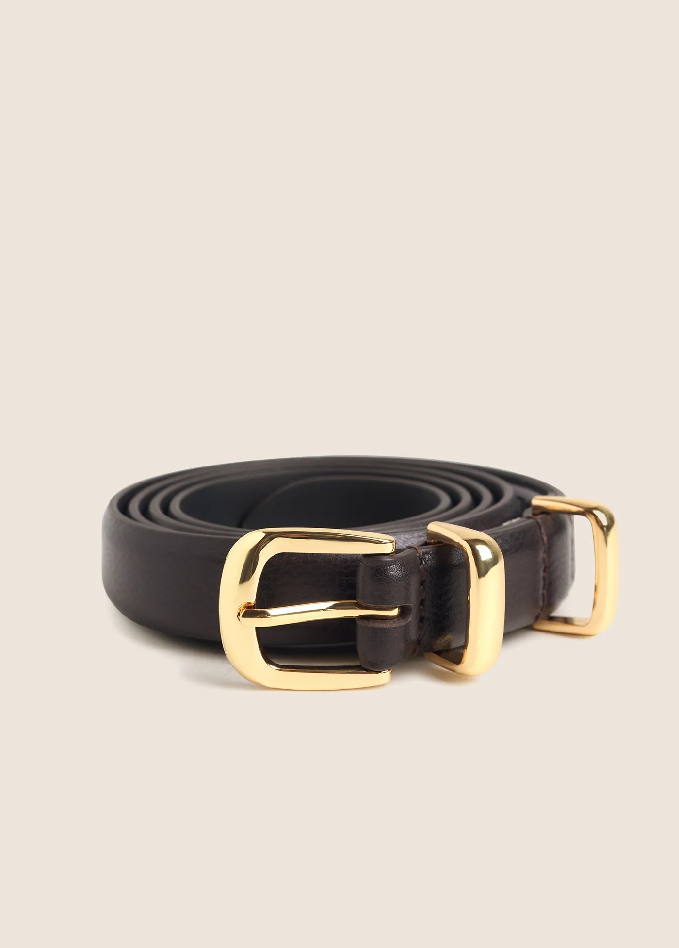 Dark brown skinny leather belt coiled with polished gold buckle and keeper loop