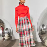Pleated plaid midi skirt with red turtleneck top and gold front buttons