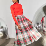 Midi-length pleated plaid skirt in red, white, and green tartan pattern