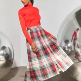 Midi-length pleated plaid skirt in red, white, and green tartan pattern