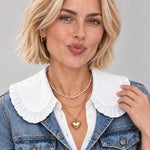 White oversized ruffle peter pan collar bib with button-front detail, worn layered