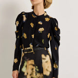 Black floral puff sleeve blouse with yellow blooms, paired with abstract print skirt
