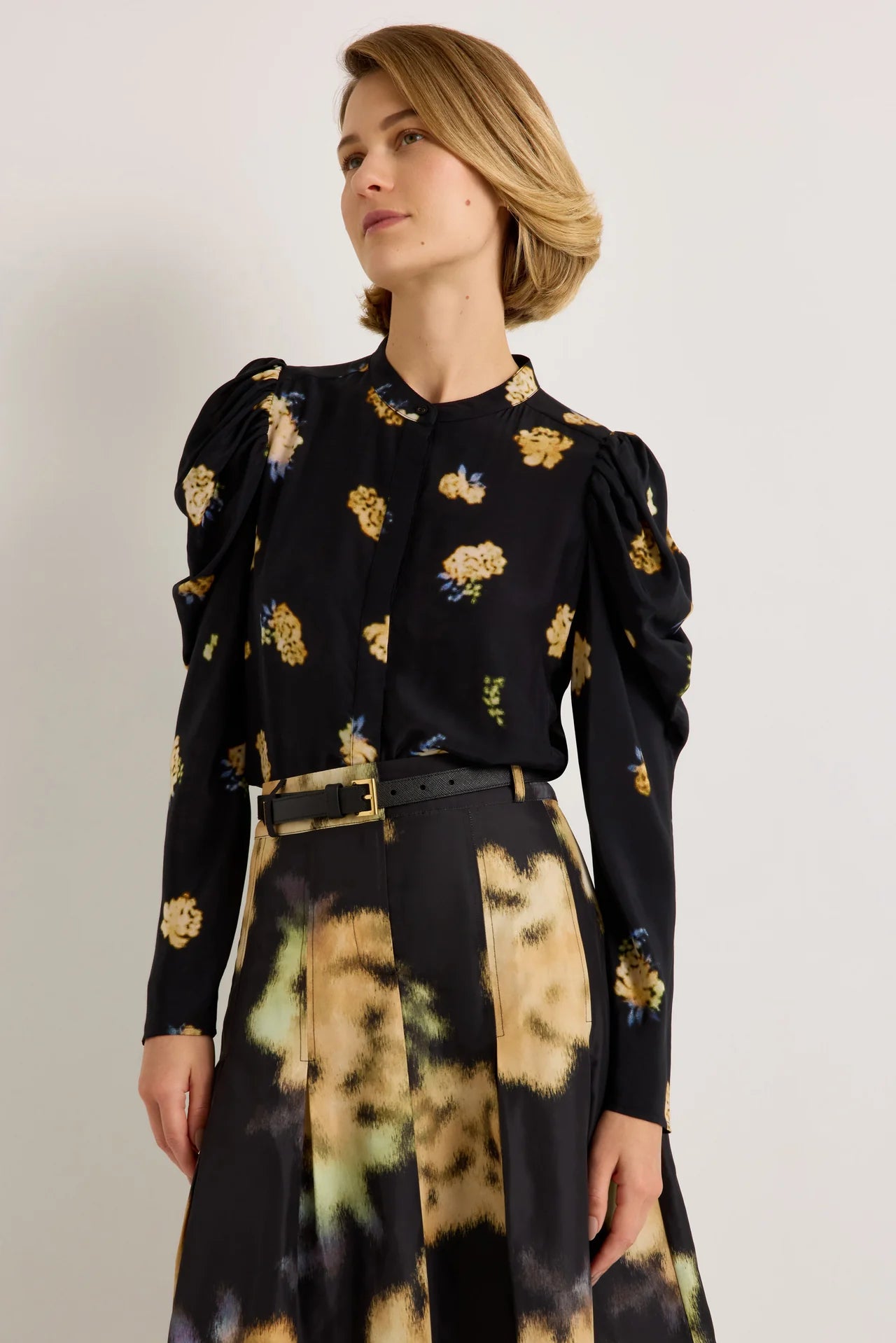 Black floral puff sleeve blouse with yellow blooms, paired with abstract print skirt