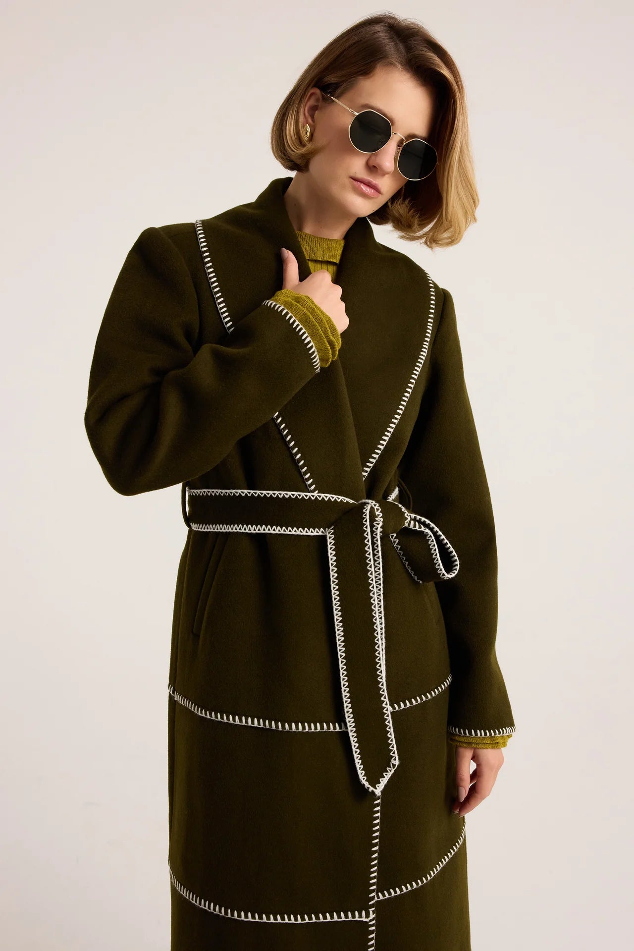 Olive green wool wrap coat with white contrast blanket stitching and self-tie belt