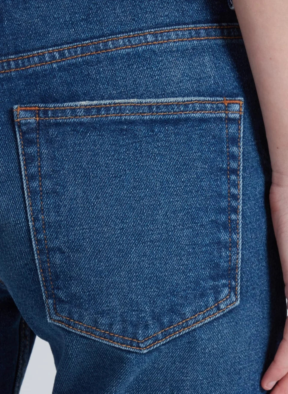 Close-up of blue denim jean back pocket with contrast orange stitching