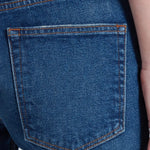 Close-up of blue denim jean back pocket with contrast orange stitching