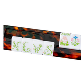 Tortoiseshell mahjong rack holding NEWS tiles, a Joker tile, and flower tile