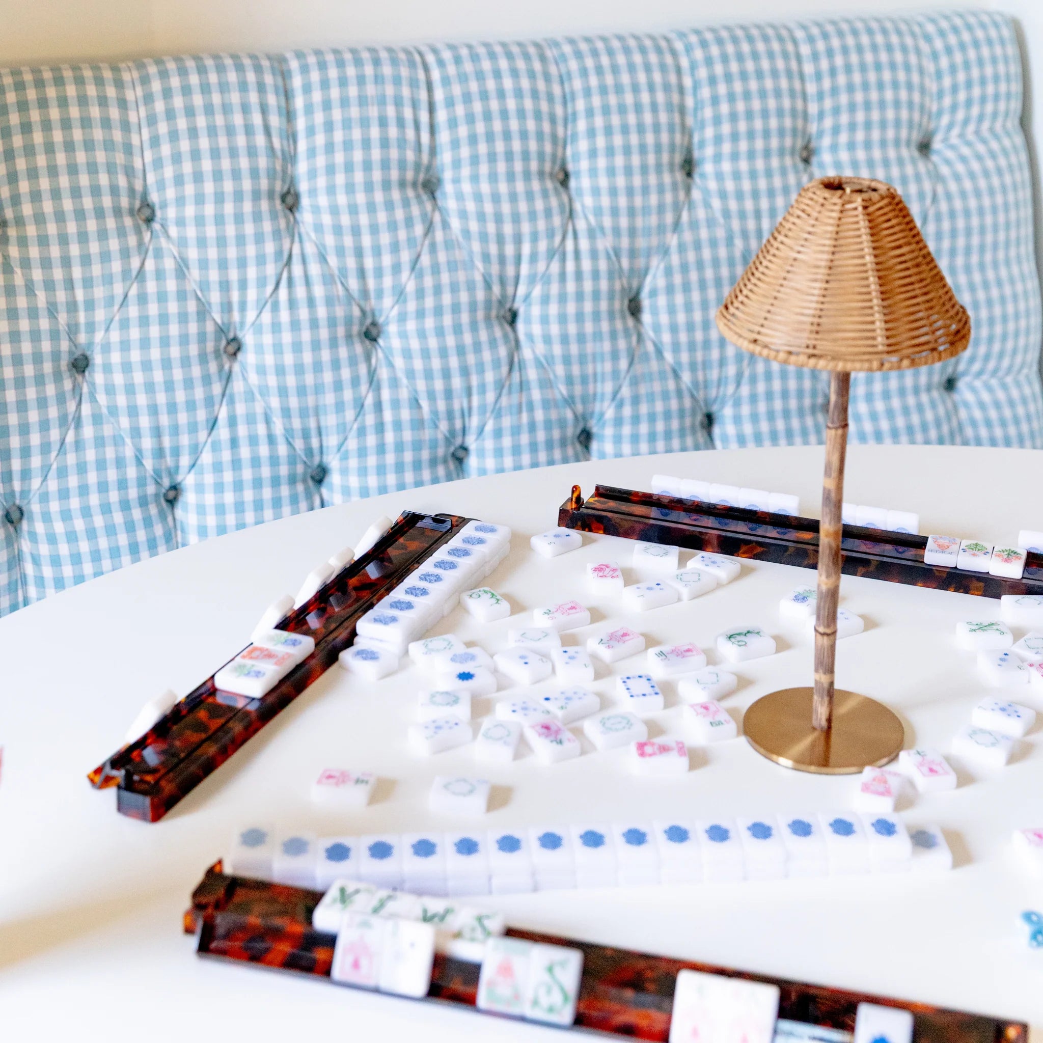 Set of four tortoise shell acrylic mahjong racks with white tiles on a white table