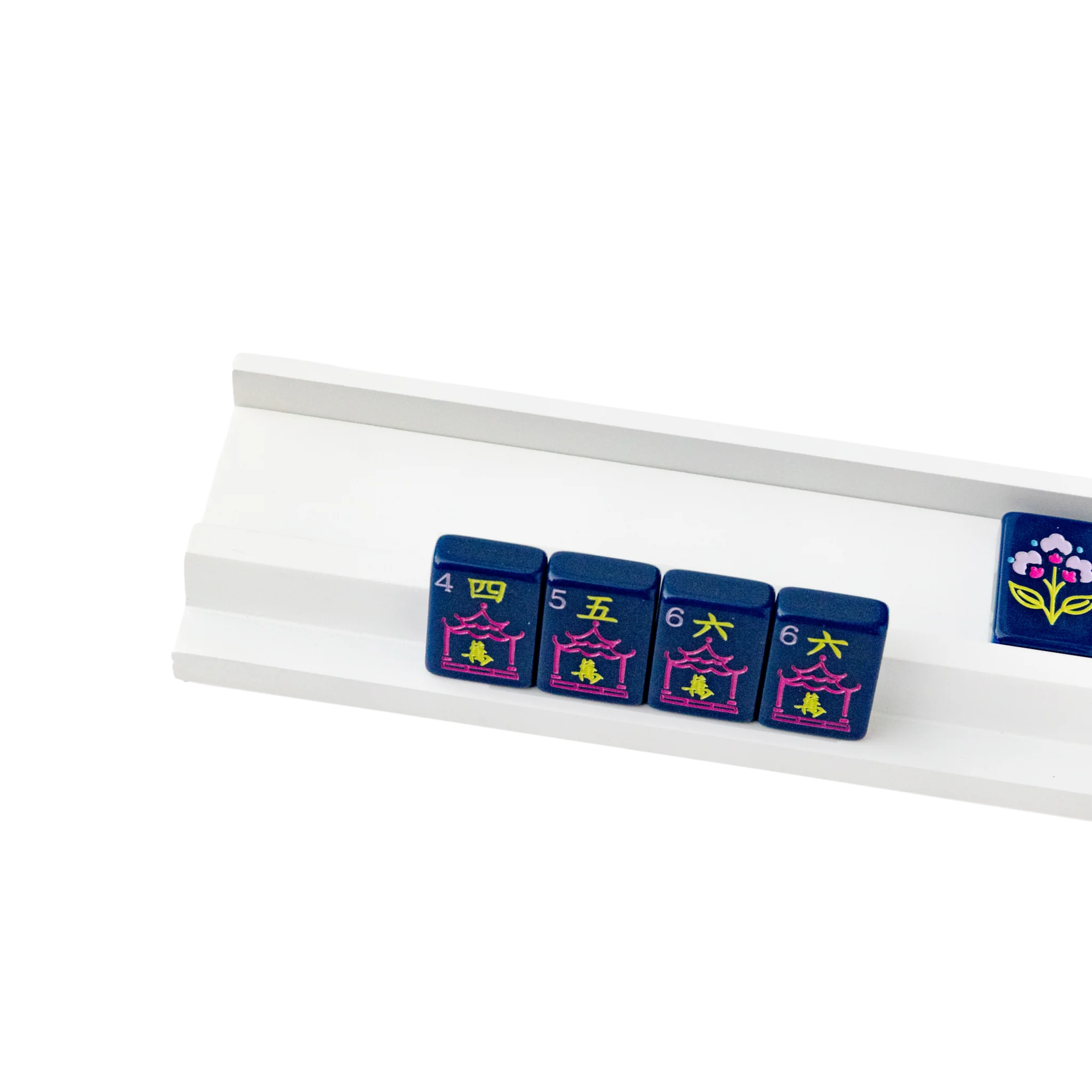 White wood mahjong rack holding navy blue mahjong tiles with pink and yellow design