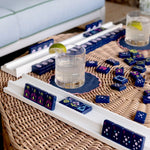White high-gloss wood mahjong racks holding navy blue decorative tiles on wicker table