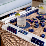 White high-gloss wood mahjong racks holding navy blue decorative tiles on wicker table
