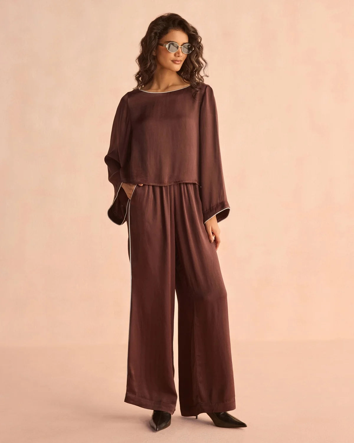 Wide-leg chocolate brown satin pants with white piping detail along side seams