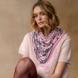 Pink cashmere bandana wrap with celestial bird print worn around neck